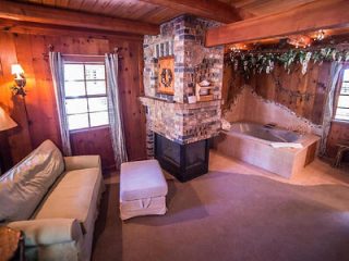 Rustic cabin living room with a stone fireplace, built-in jacuzzi, and comfortable white sofa.